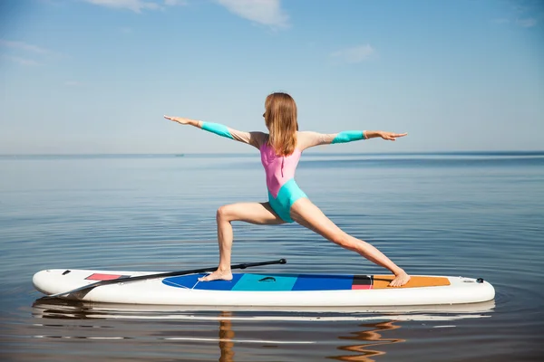 Woman doing yoga on sup board with paddle — Stock Photo, Image