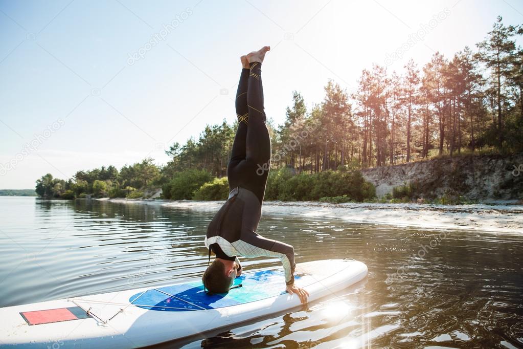 Man doing yoga on sup board with paddle