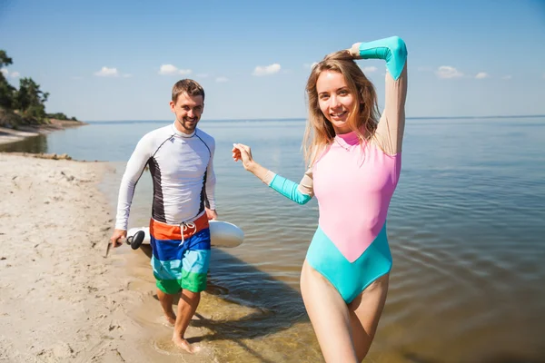 Young couple walking with sup board — Stock Photo, Image