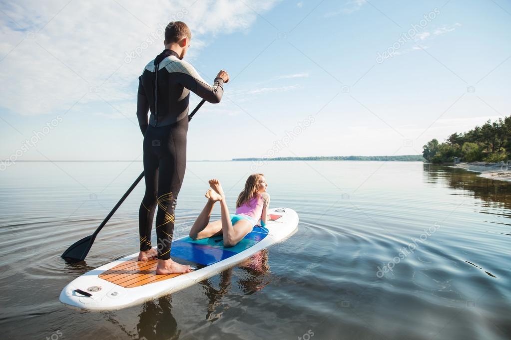 Young couple paddling on sup board Stock Photo by
