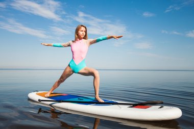 Woman doing yoga pranayam on sup board with paddle clipart
