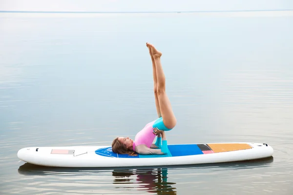 Woman doing yoga on sup board with paddle — Stock Photo, Image