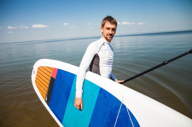 Sup kurulu ve raket sahilde - doğa, ücretsiz ve sağlıklı yaşam, serbest, uzak iş ile uyum kavramı ile genç adam.