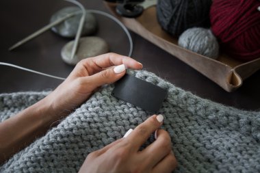 Woman sewing the genuine leather lable 