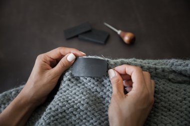Woman sewing the genuine leather lable  clipart
