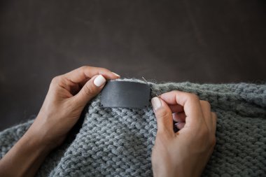 Woman sewing the genuine leather lable 