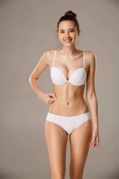 Женщина щипает кожу на животе, проверяя подкожный жировой слой.