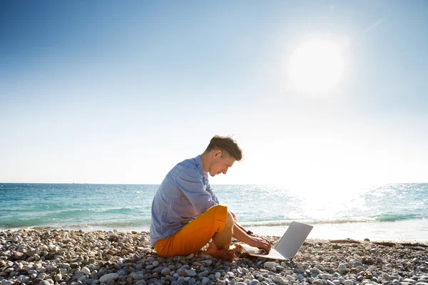 Homem andando com computador portátil pela costa do mar — Fotografia de Stock