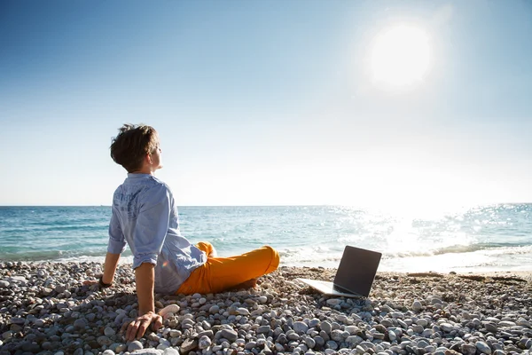 Man walking with laptop computer by the sea coast — Stock Photo, Image