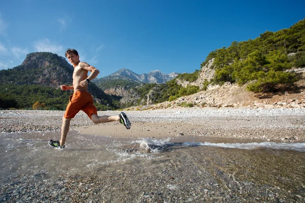 Hombre corriendo al amanecer en el agua — Foto de Stock