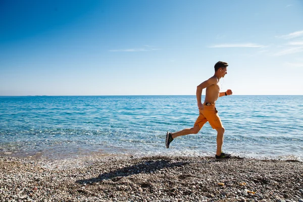 Hombre corriendo al amanecer en el agua — Foto de Stock