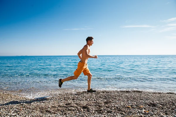 Hombre corriendo al amanecer en el agua — Foto de Stock