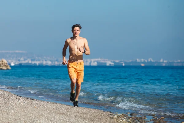 Hombre corriendo al amanecer en el agua — Foto de Stock