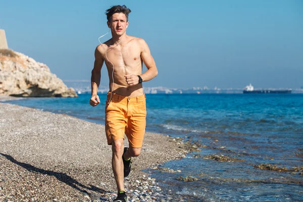 Hombre corriendo al amanecer en el agua — Foto de Stock