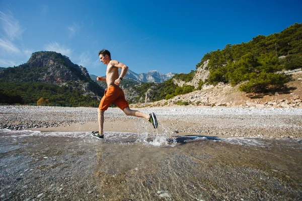 Man running at sunrise on the water — Stock Photo, Image