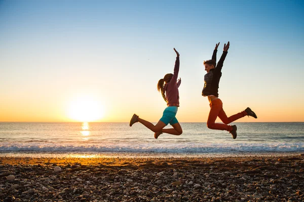 Couple jumps on the beach over sunrise — Stock Photo, Image