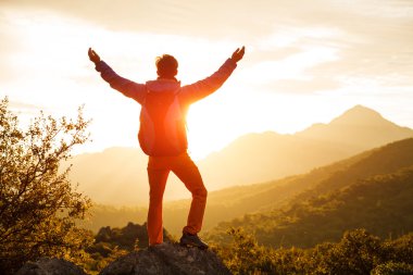 Uzun yürüyüşe çıkan kimse cliff üzerinde güneşin üzerinde duruyor.