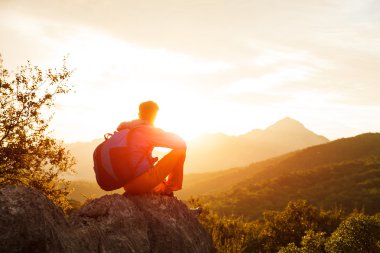 Uzun yürüyüşe çıkan kimse cliff üzerinde güneşin üzerinde duruyor.