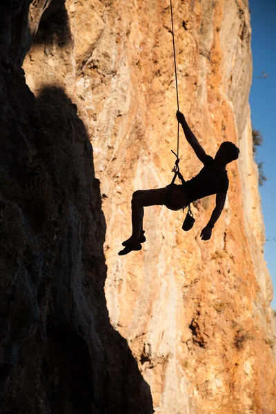 Silueta de escalador colgando de la cuerda de abajo contra las montañas — Foto de Stock