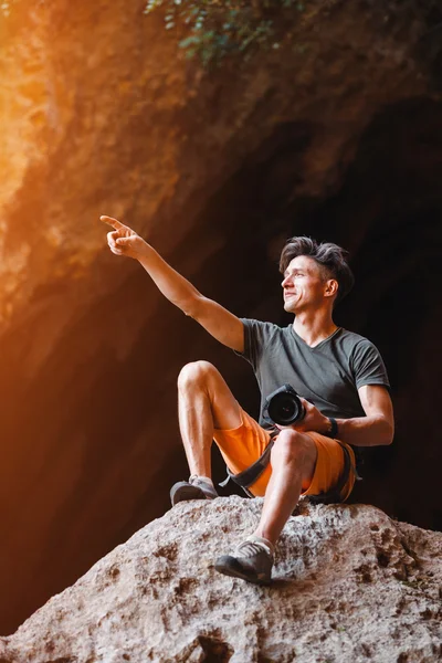 Male photographer on the cliff pointing by his hand