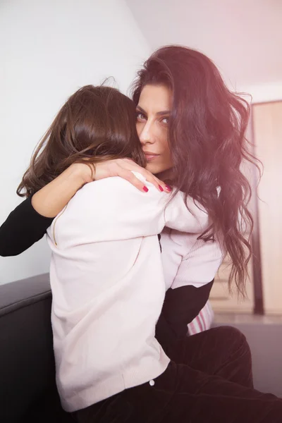 Genç anne ve kızı koltukta sarılma — Stok fotoğraf