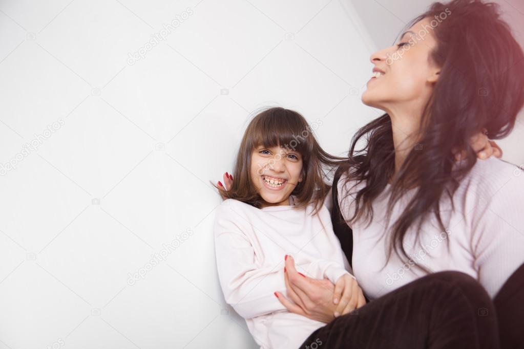 Young mother and daughter having fun on the sofa