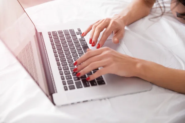 Primer plano de las manos de la mujer con el ordenador portátil en la cama —  Fotos de Stock