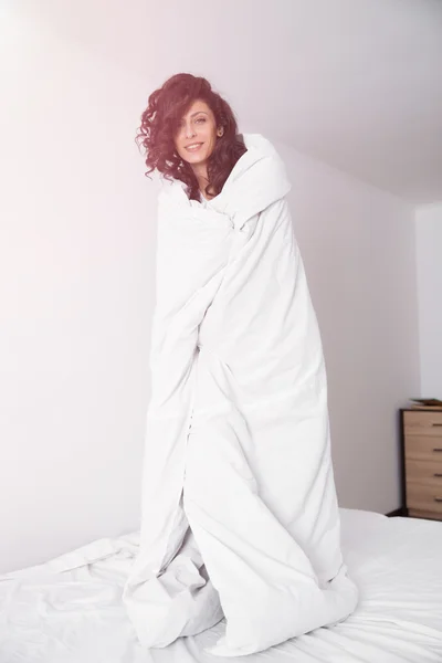 Beyaz yorgan hite yatakta esmer kadın kapsadığı — Stok fotoğraf