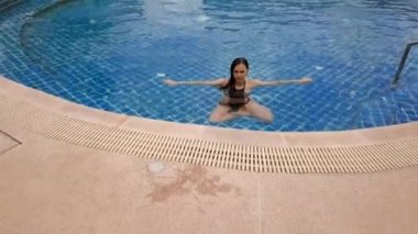 Açık mavi yüzme havuzunda yüzen genç bir kadın. Açık hava aktiviteleri. Sağlıklı bir yaşam tarzı. Üst görüntü video 4k.