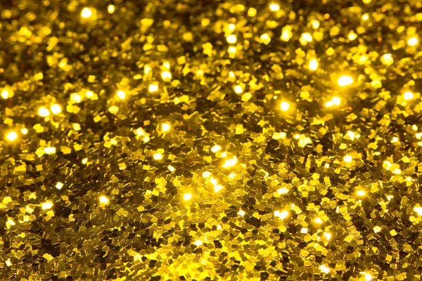 Gold glitter texture. Festive sparkling sequins background closeup. Brilliant shiny walpaper for the day of St. Valentine, New Year and Christmas Holidays.