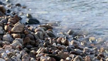 Sörf günbatımında çakıl taşı plajını yıkar..