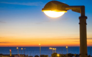 Turuncu bir gün batımı, gece gökyüzü ve bir sokak lambası..