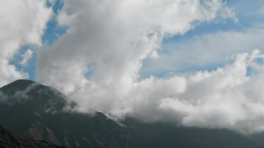 Zaman bulutları bir dağ vadisinde kıvrılır. Uzakta karlı bir tepe. Mustang, Nepal, Annapurna