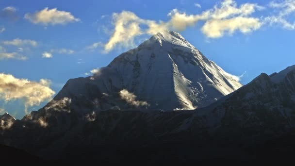 Timelapse del inicio de la noche en un pico nevado, brillo de hielo al atardecer, nubes giran sobre la cima de la montaña — Vídeos de Stock