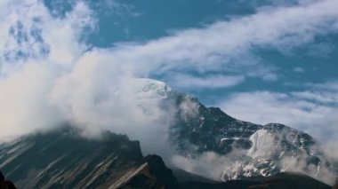 Zaman bulutları bir dağ vadisinde kıvrılır. Uzakta karlı bir tepe. Mustang, Nepal, Annapurna