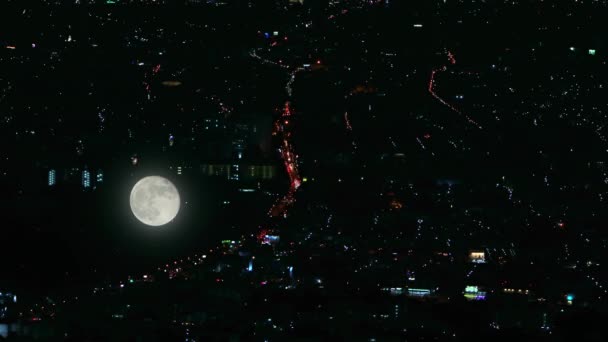 Luna llena reflejada en vidrio sobre el fondo de las luces nocturnas de la ciudad — Vídeos de Stock