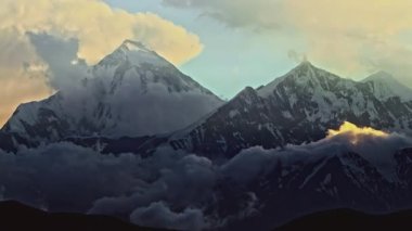 Karlı bir zirvede gecenin başlangıcının zamanlaması. Bulutlar Nilgiri Dağı 'nın zirvesinde dönüyor.