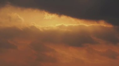 Güneşin parlak diski bulutların arasından günbatımında parlayan gökyüzünde hareket eder.