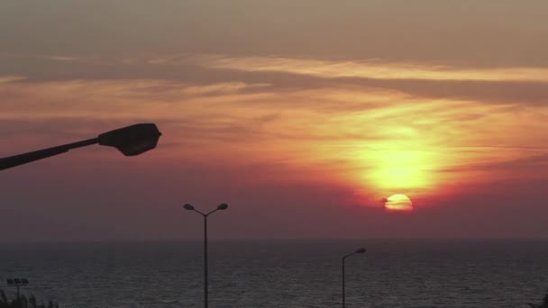 Puesta de sol naranja sobre el mar. Vista desde la casa, con farolas. — Vídeos de Stock
