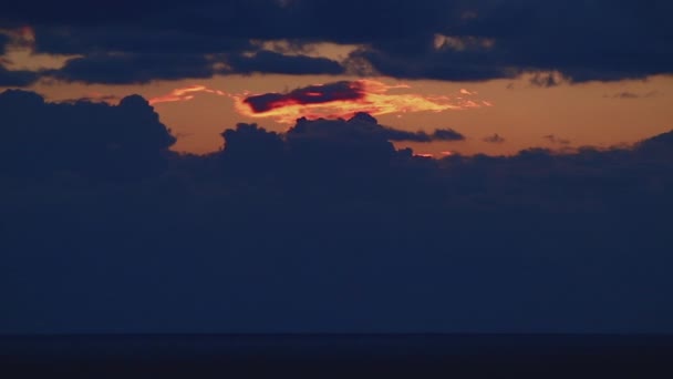 Zeitraffer, eine große Sonne geht unter in orangen Wolken, die sich blau färben. — Stockvideo