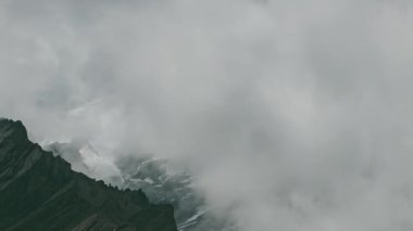 Zaman bulutları bir dağ vadisinde kıvrılır. Uzakta karlı bir tepe. Mustang, Nepal, Annapurna
