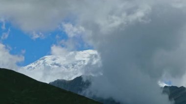 Zaman bulutları bir dağ vadisinde kıvrılır. Uzakta karlı bir tepe. Mustang, Nepal, Annapurna