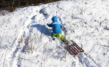 Kış çocuk oyunları, güneşli bir günde kızakla kayma. Şehir parkında ya da kırsal kesimde kış çocuk eğlencesi..