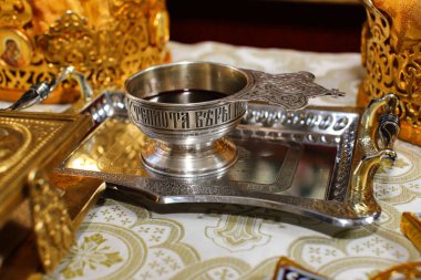 Ortodoks kilisesinin masasında altın madalyayla süslenmiş düğün çelenkleri, İncil ve haç bulunuyor. Atmosfer kutsal kilisenin düğününü sembolize ediyor. Yazıtta 