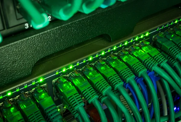 绿色网络电缆连接到交换机在黑暗中发光的特写 — 图库照片