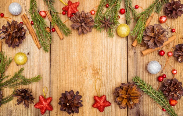 Juldekoration på rustika trä skrivbord (tall kottar, kanel, anis, spruce grenar, röda stjärnor) — Stockfoto