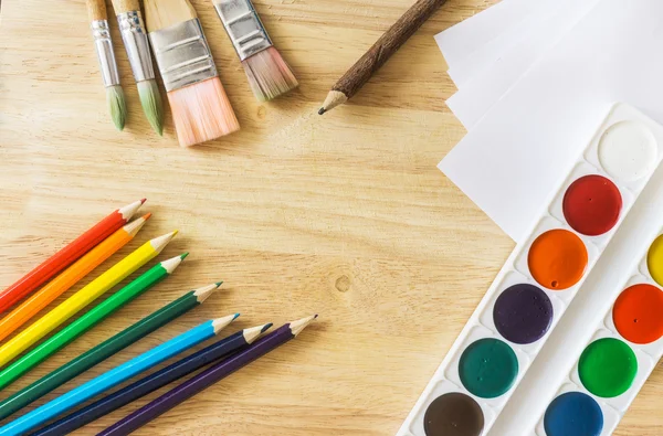 Pincéis de pintura, lápis de cor, papel branco e aquarela sobre fundo de madeira — Fotografia de Stock