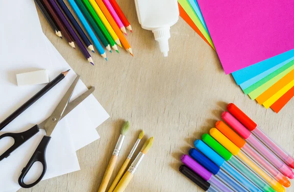 Papel colorido, canetas de feltro, lápis, pincéis sobre fundo de madeira — Fotografia de Stock