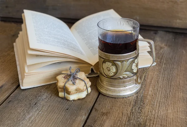 Kniha, soubory cookie a čaj v dráze na dřevěné pozadí — Stock fotografie