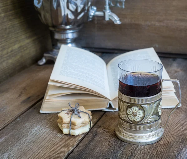 Libro, galletas y té en posavasos sobre fondo de madera —  Fotos de Stock